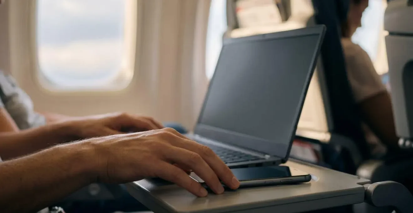 Mobile phone serving as WiFi hotspot alongside laptop in travel workspace environment
