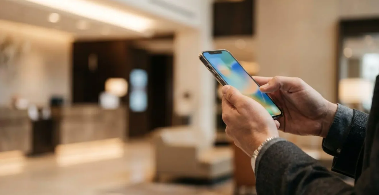 Business traveler discreetly testing WiFi connection speed on smartphone in upscale hotel lobby before check-in