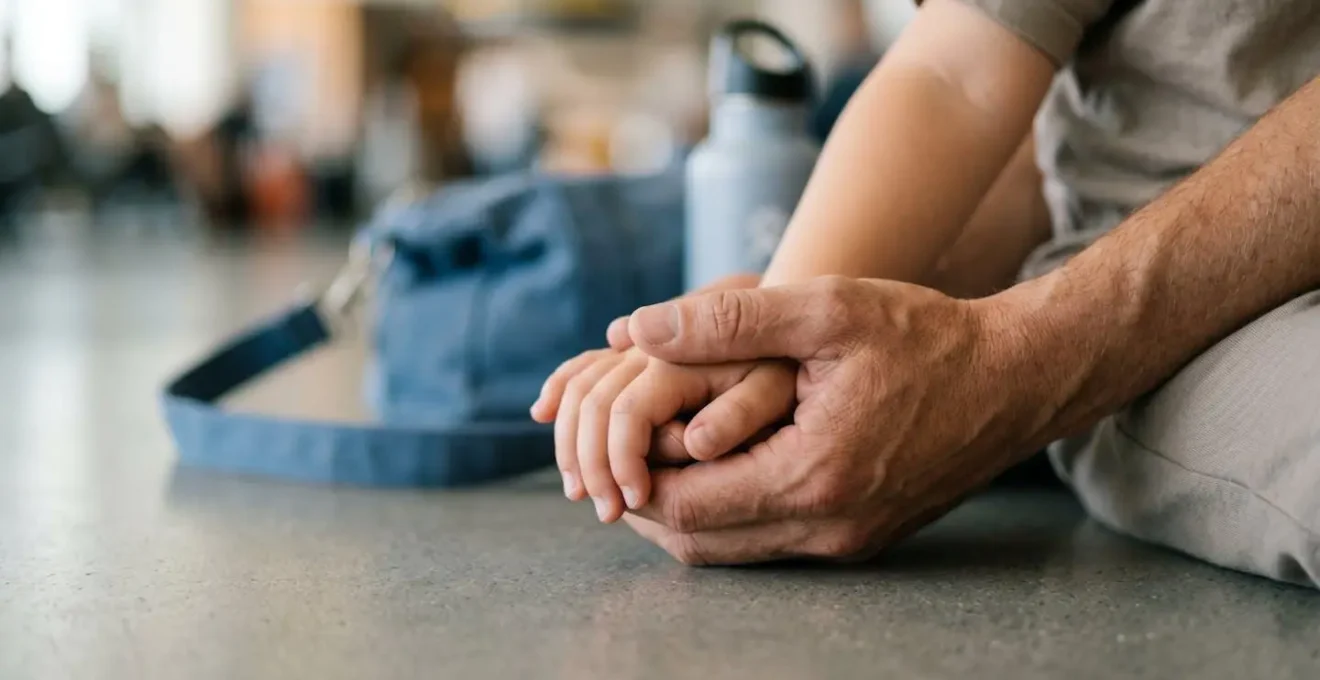 Close-up of parent and child hands during quiet airport moment showing calm connection
