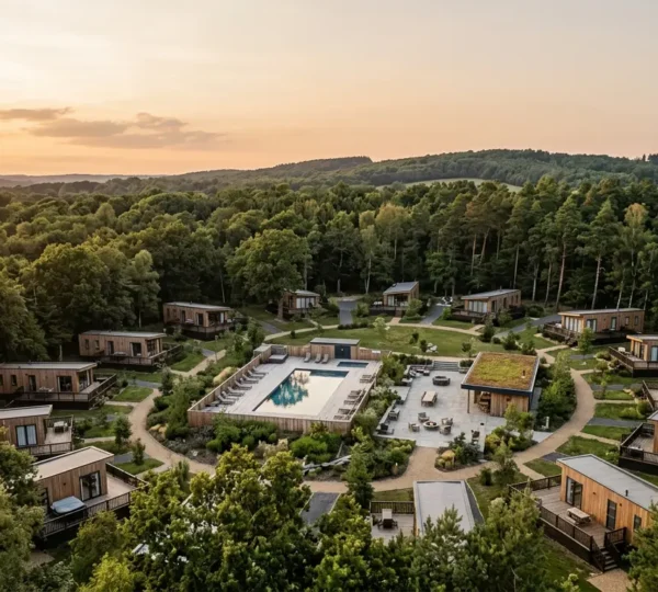 Aerial view of a modern residential leisure park with individual lodges nestled among natural woodland, showcasing the hybrid accommodation model between hotels and self-catering