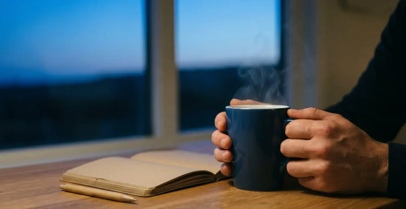 Close-up of traveler's hands holding warm beverage near window during evening reflection moment